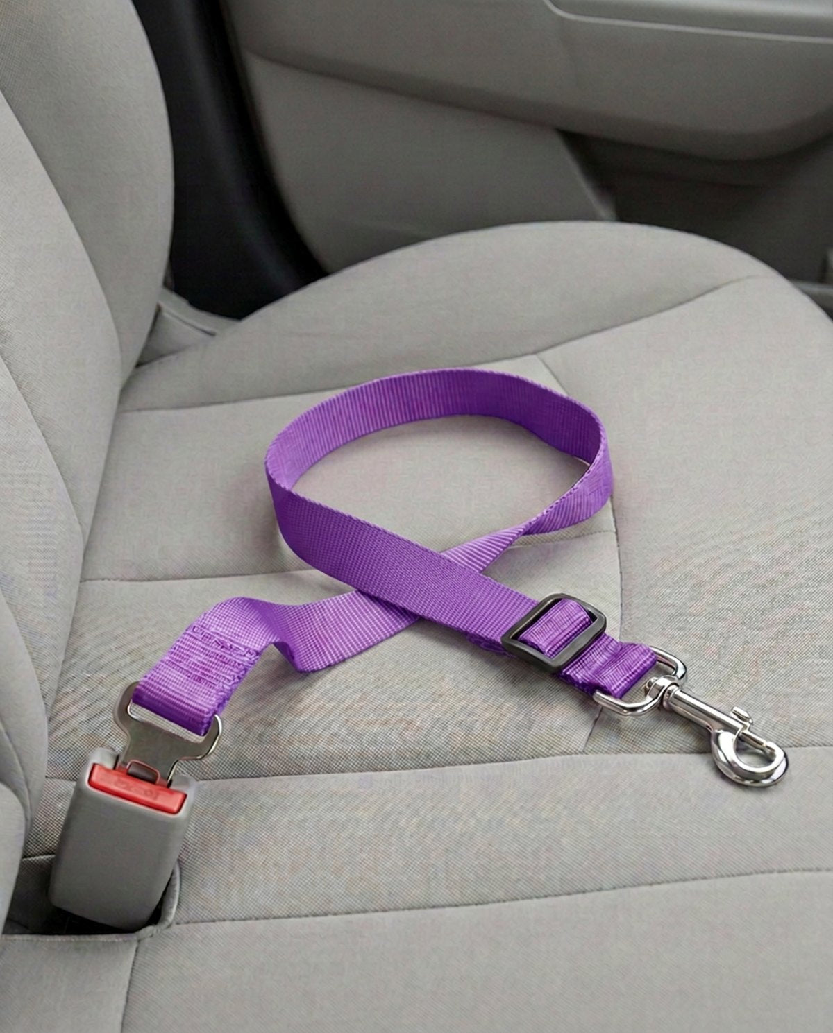 Cinturón de seguridad para coche en morado, abrochado a la hebilla del asiento del copiloto