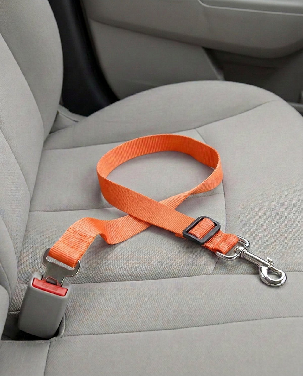 Cinturón de seguridad para coche en naranja, abrochado a la hebilla del asiento del copiloto